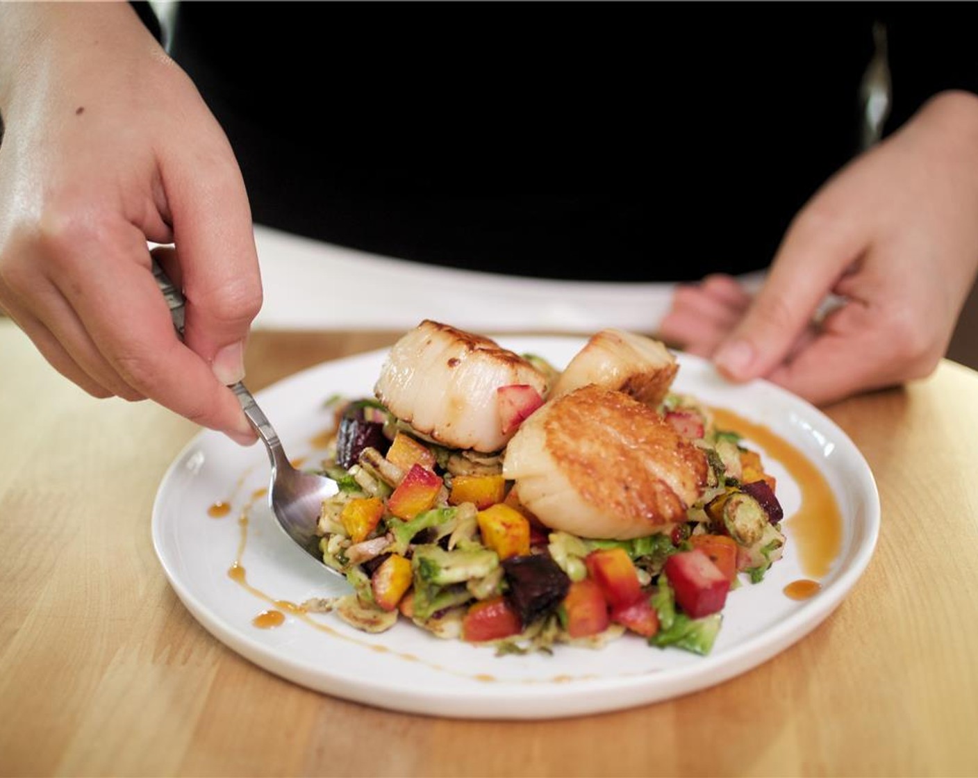 step 10 Place the roasted potatoes, beets, and Brussels sprouts in the center of two plates. Place three scallops on top of the veggies on each plate with the golden seared side facing up. Spoon the cider gastrique all around.