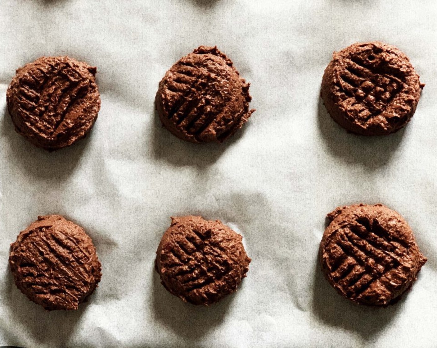 step 4 Divide into 12 balls and place on a parchment-lined tray, gently press them down with the back of a fork.