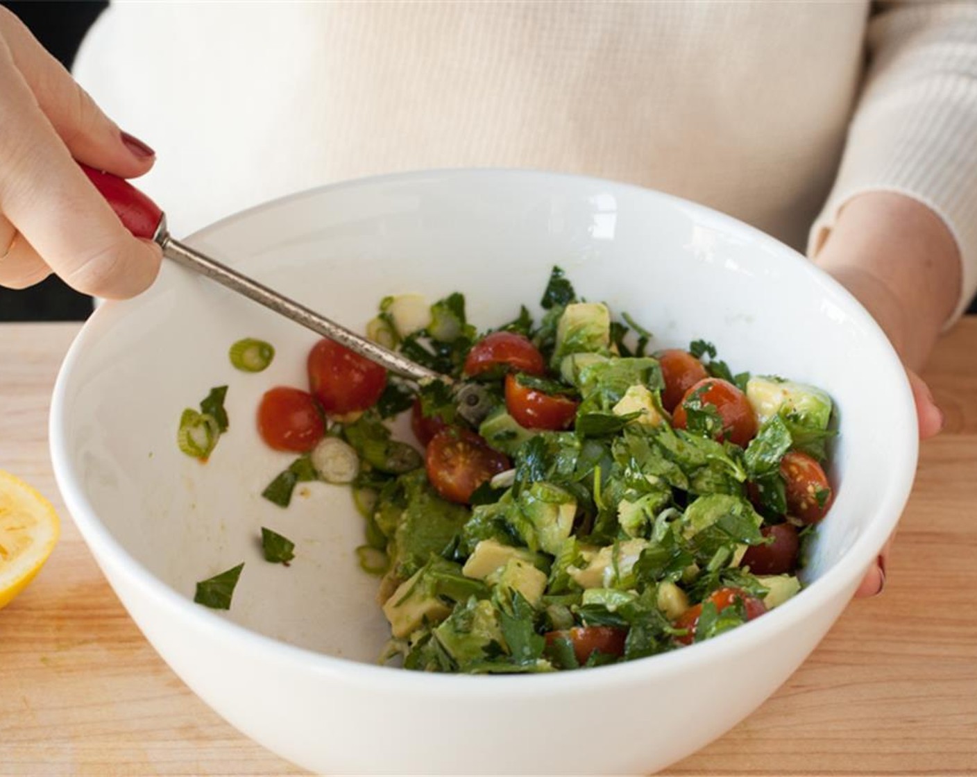 step 3 Scoop out half an Avocado (1) and cut into cubes. In a medium bowl, combine avocado, cherry tomatoes, scallions, and parsley. Add juice of 1/2 of the lemon and toss to coat. Taste and add salt and pepper as needed. Set aside.