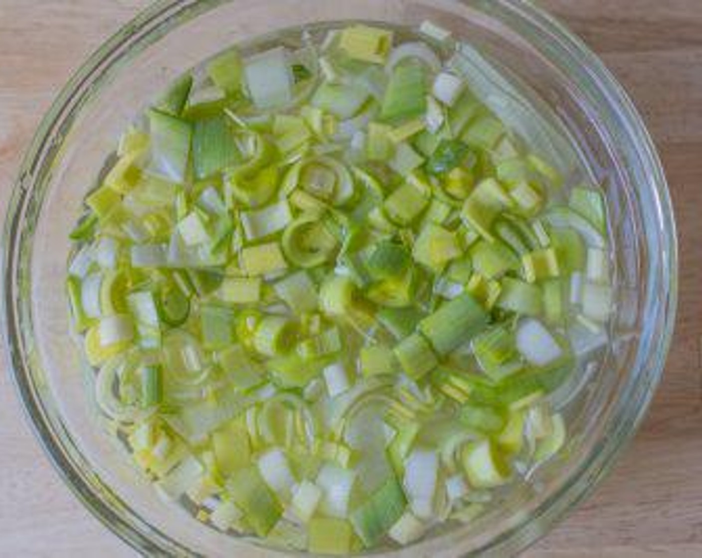 step 1 Cut off the dark green stem and the root off the Leek (1) .Cut the white and light green parts only of the leek lengthwise down the middle, then cut into ½ inch half moons slices. Place leek pieces in a large bowl of water and separate the pieces with your hands to clean the dirt off. Lift the cleaned pieces out of the dirty water and set aside. Throw out the dirty water.