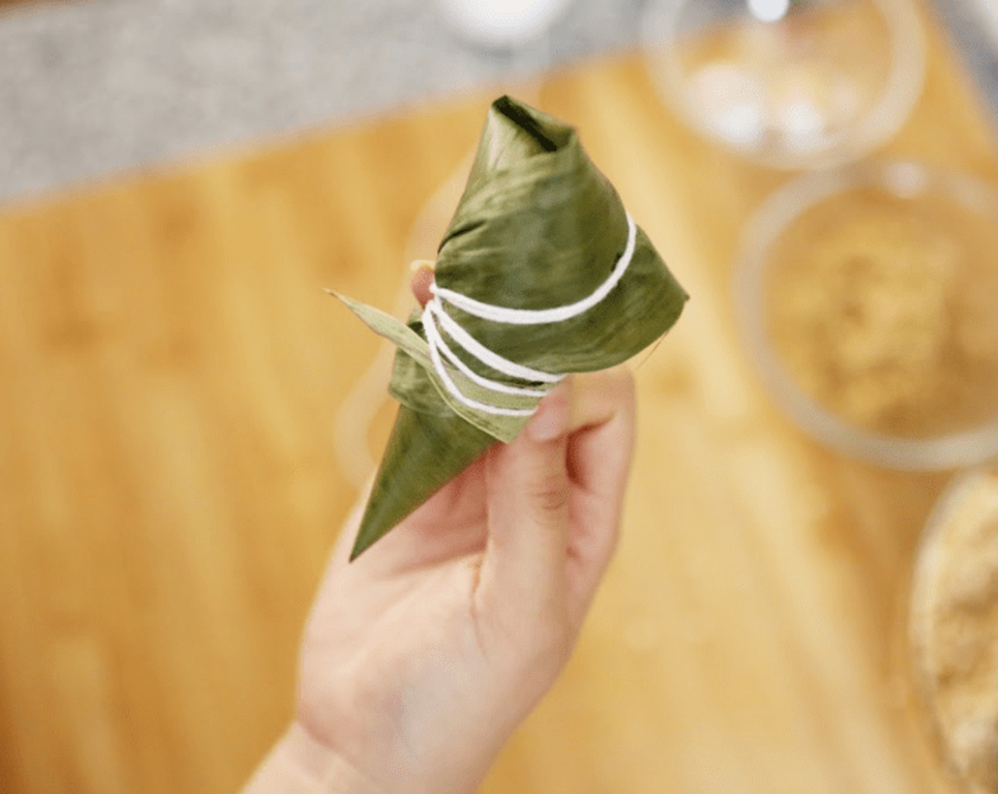 step 9 Finally filled with glutinous rice again, but do not fill the leaf to the top. With the palm leaf facing down on a flat surface, wrap the dumplings with a cotton line.