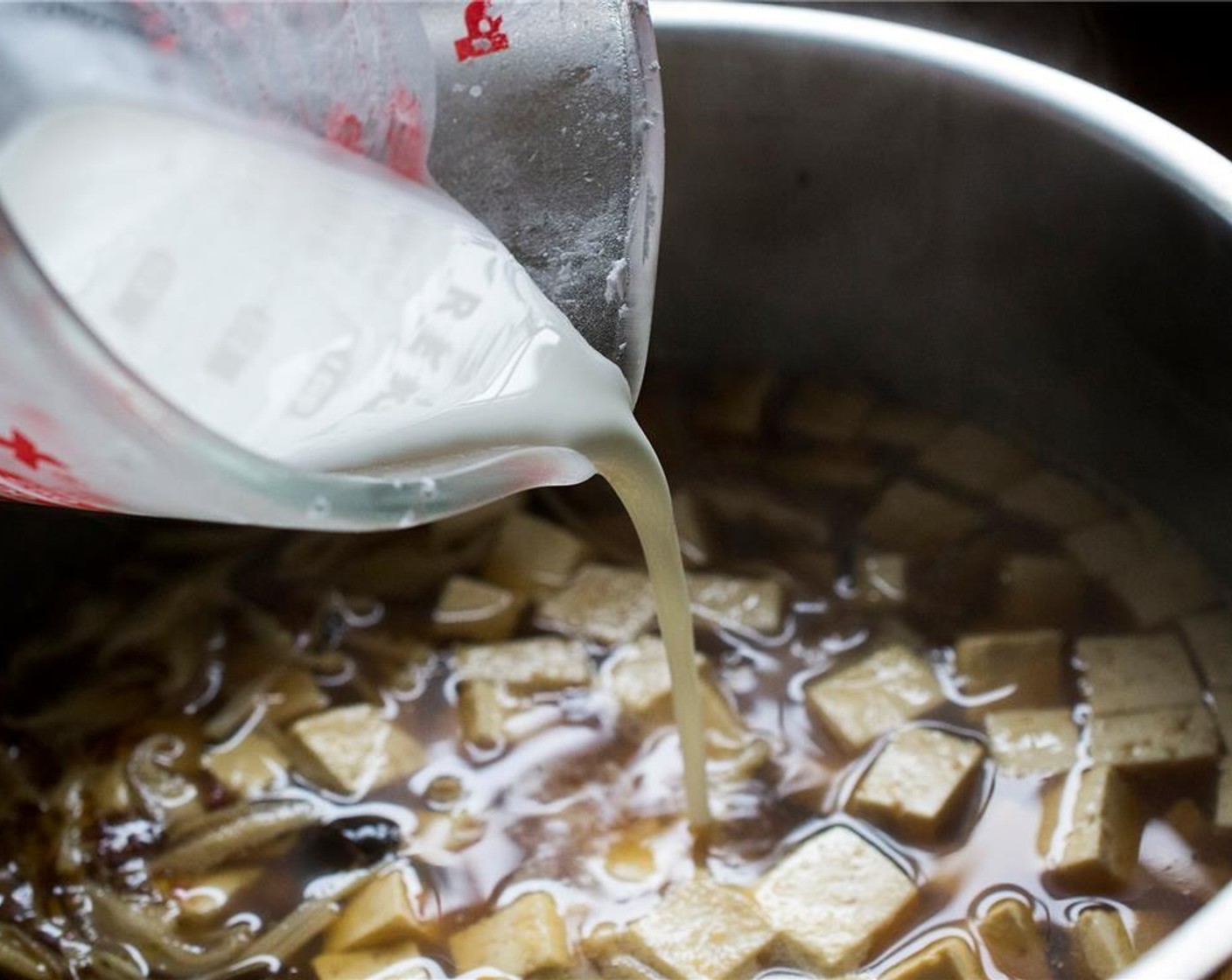 step 10 To the pot, add Sesame Oil (1/2 Tbsp), pork loin, Bamboo Shoots (1 1/2 cups), Enoki Mushroom (1/2 cup), shiitake mushrooms, and wood ear mushrooms. Bring to a boil and then reduce to a simmer.