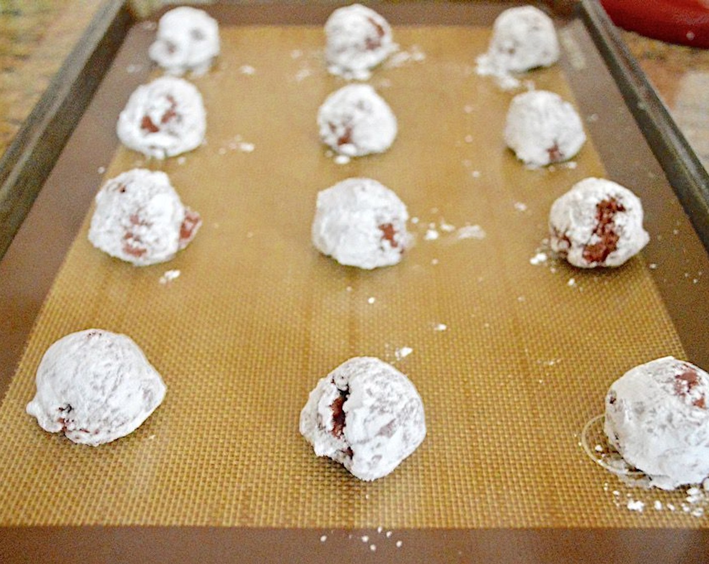 step 6 Use a 1.5-inch cookie scoop to get perfect mounds of dough, then coat each of them in the powdered sugar before lining them up on the cookie sheet. The first two sheets will accommodate half of the dough, so put the rest back in the refrigerator while you bake the first batch for about 12-13 minutes.