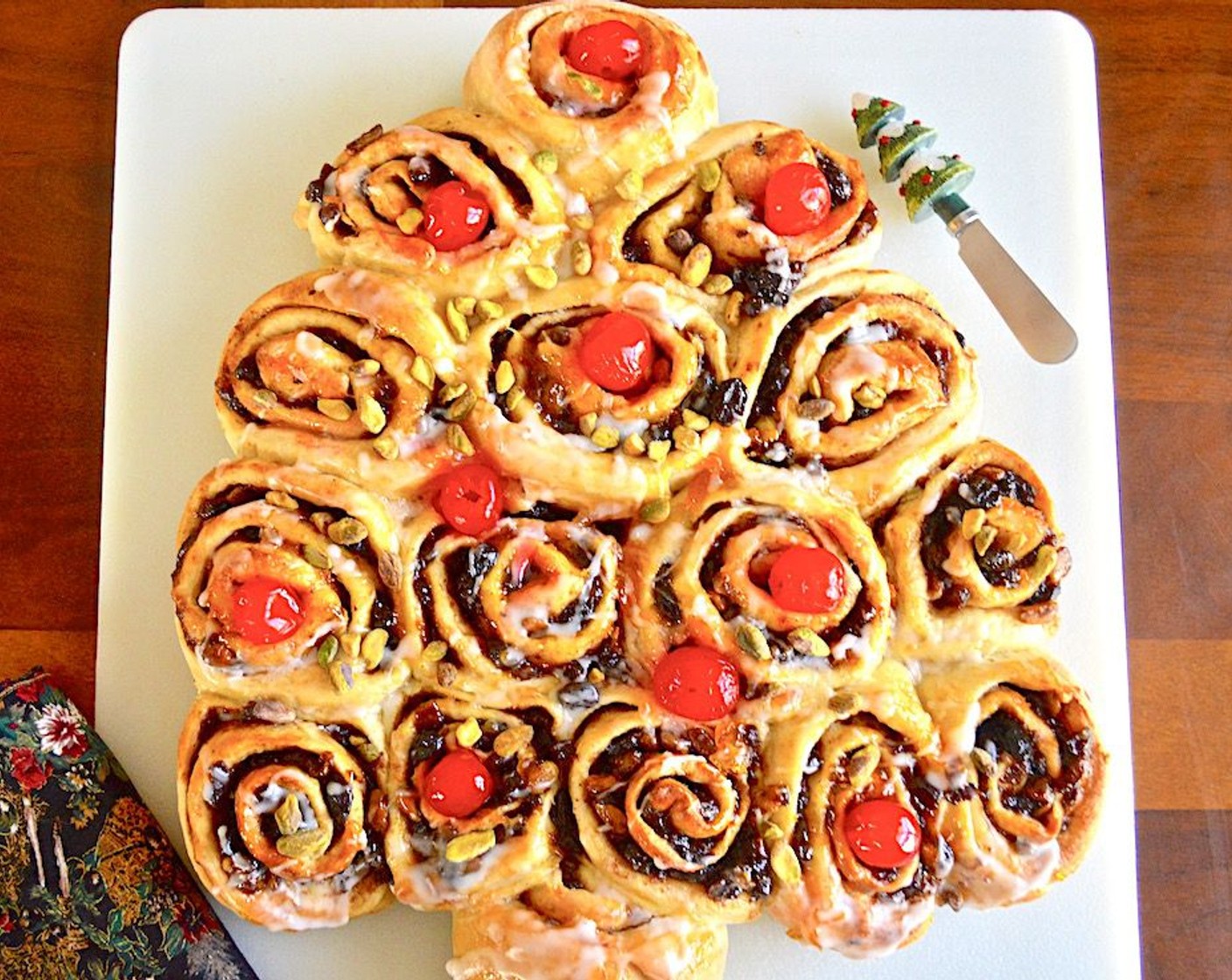 step 14 When the chelsea bun tree is done, brush it all over with the apricot glaze to give it a shine. Then drizzle it generously all over with the icing to look like snow and place the Maraschino Cherries (10) and chopped pistachios on top. Serve immediately.