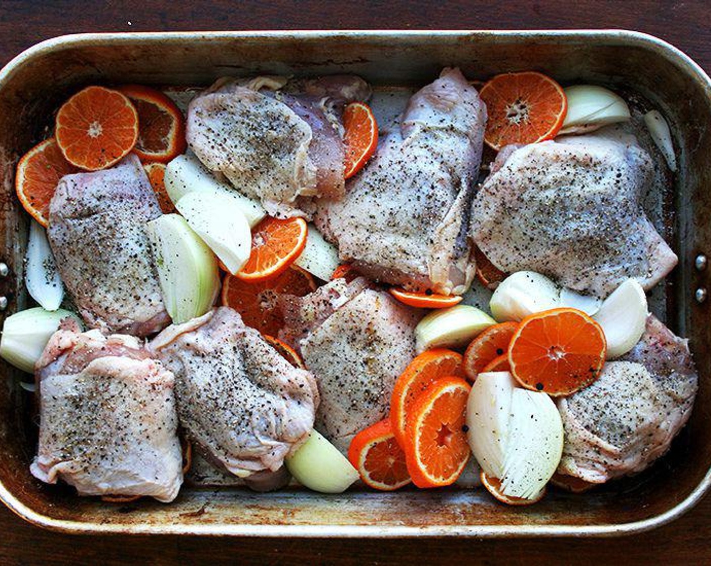 step 5 If roasting immediately: Place the Chicken Thighs skin side up in a large roasting pan with clementine slices, thyme, onion quarters and crushed fennel seeds.
