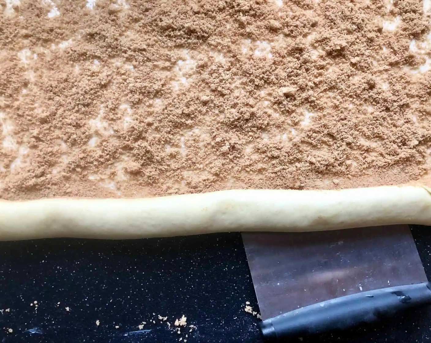 step 7 Starting with the long edge closest to you, tightly roll up the dough into a log. Pinch along the edges of the log to seal it as you proceed.