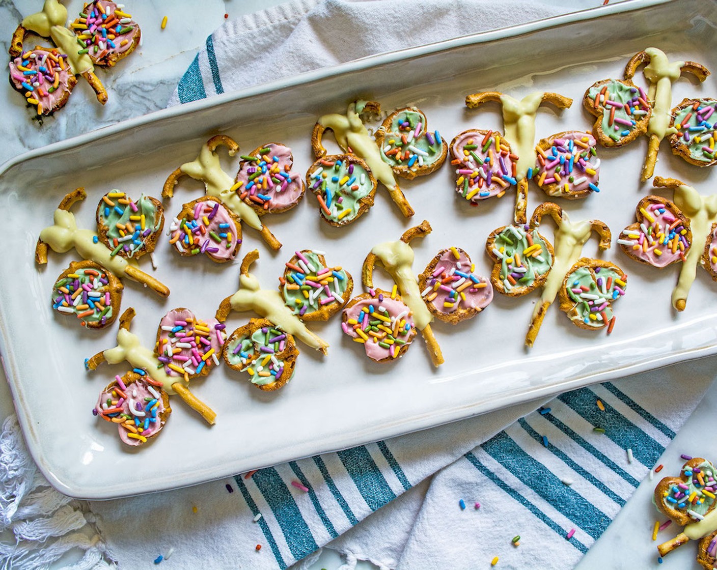 step 18 Pipe the warm pink-colored chocolate into the “wings” of the remaining butterflies, smooth once again with the cake spatula, then sprinkle with the rainbow sprinkles and return to the refrigerator for another 10 minutes or so.