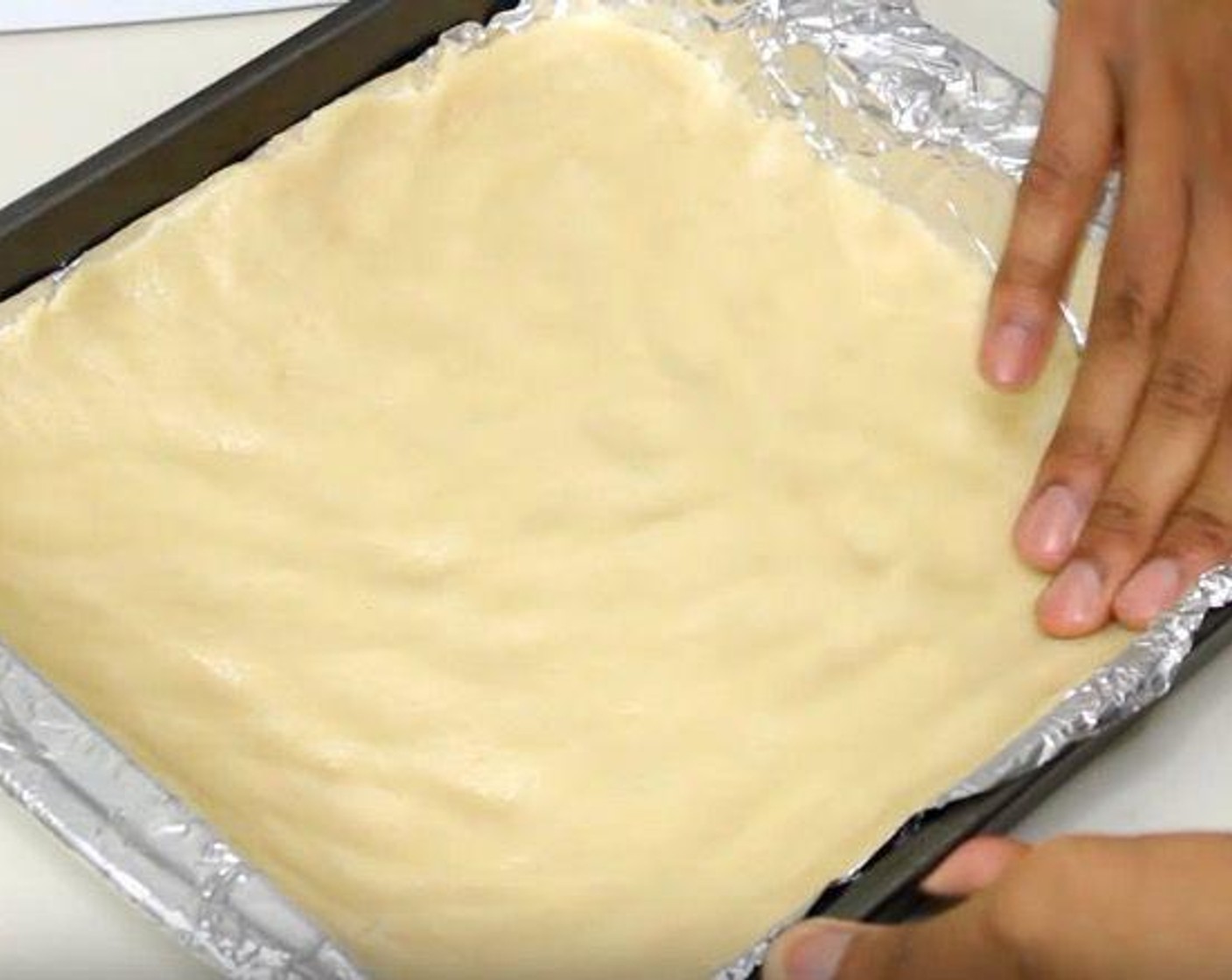 step 2 Transfer the dough to a 9-inch square pan lined with aluminum foil. Press it down into an even layer.