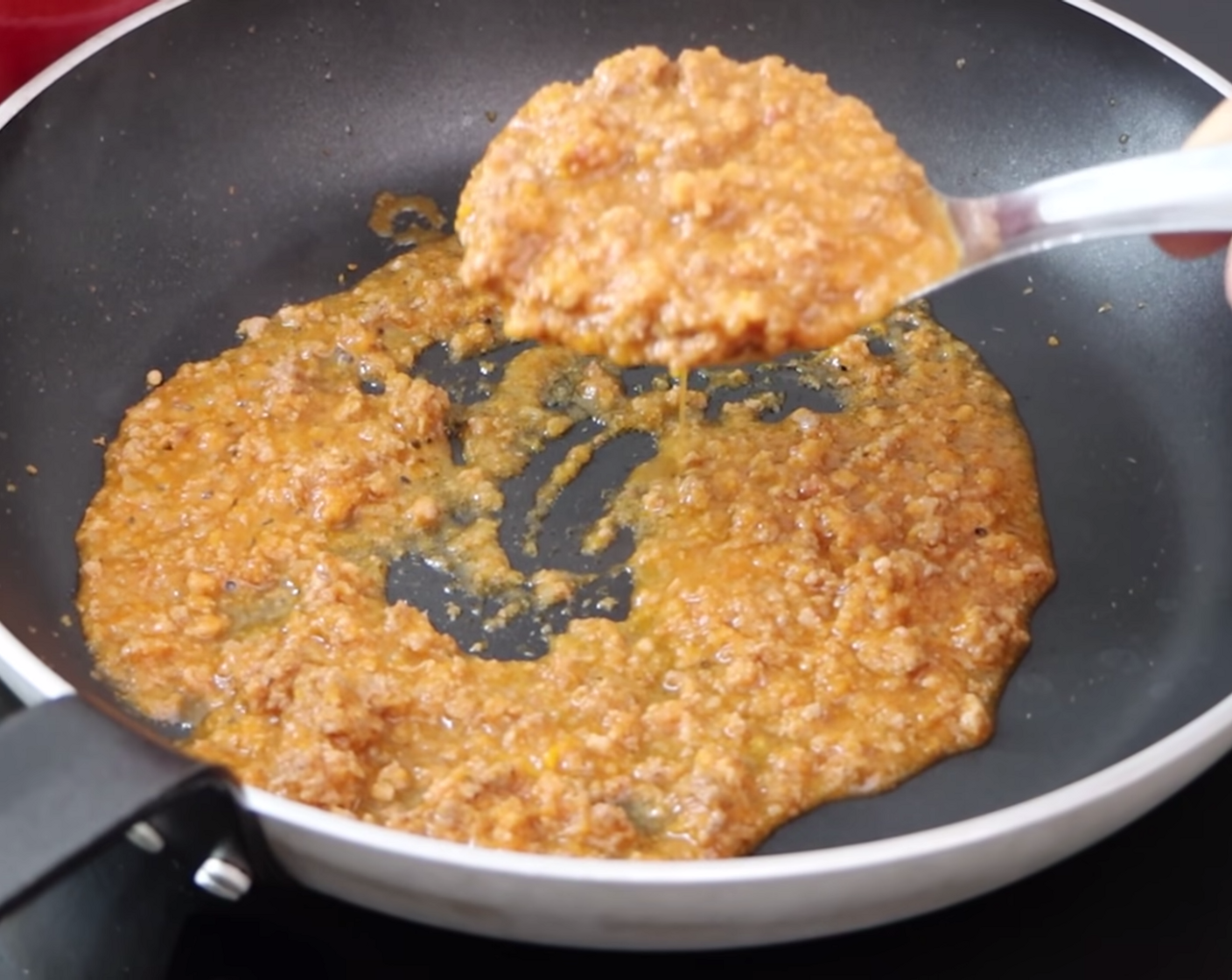 step 13 While the pasta is boiling, prepare a large frying pan for mixing. Place a frying pan on the stove at low heat, and add a generous spoonful (or two!) of Bolognese sauce, covering the bottom.