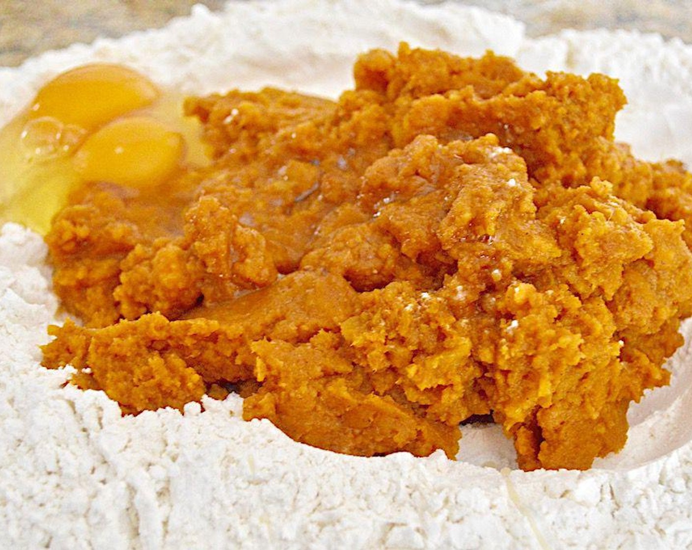 step 4 On a clean counter surface, make a big well with the All-Purpose Flour (435 g) and spoon the pumpkin sweet potato mixture into it. Crack the Eggs (2) on top. Then use a fork to start beating the eggs while  you start to incorporate the wet ingredients into the flour. Switch to using your clean hands to bring the dough into a smooth ball.