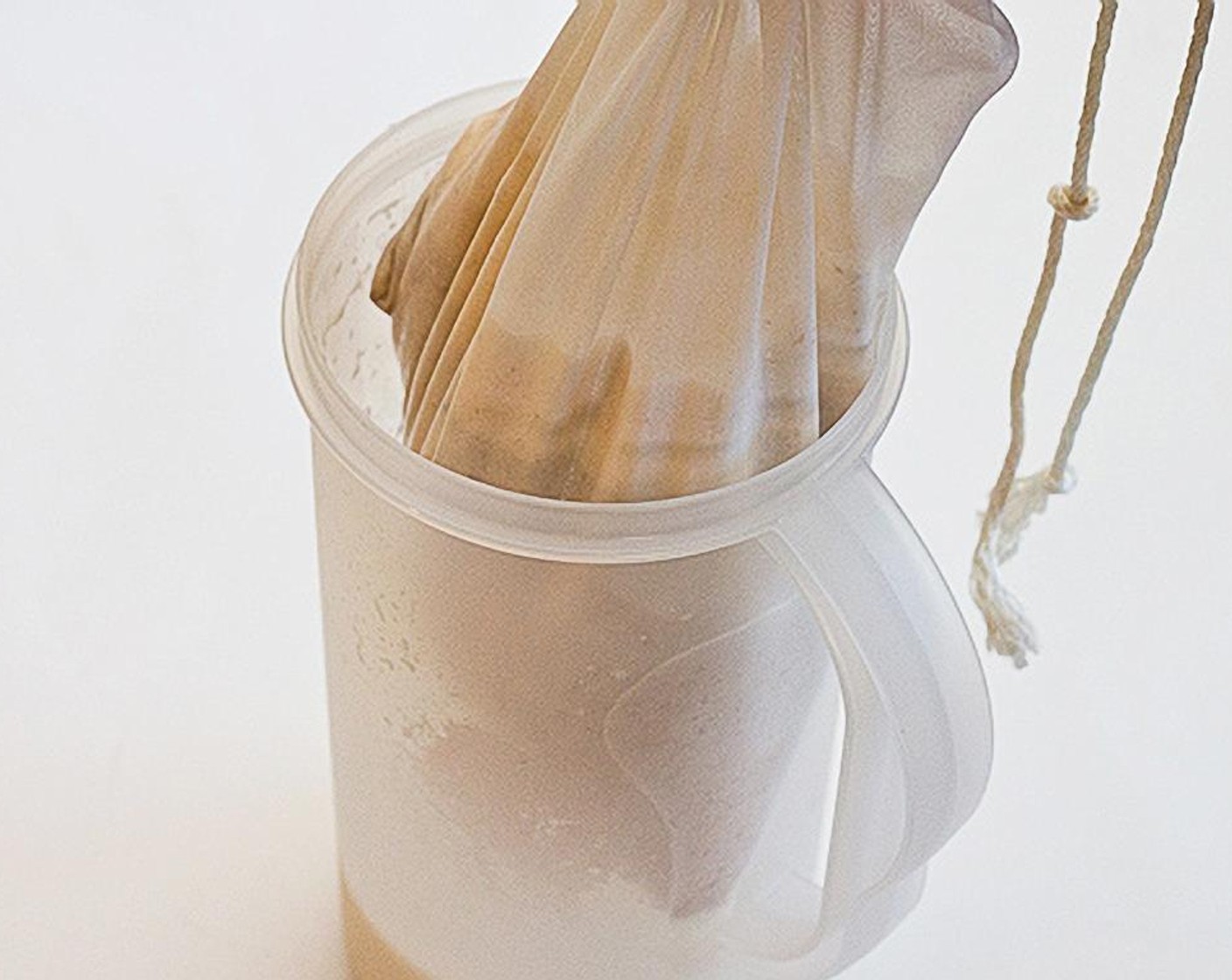 step 5 Prepare a container (pitcher, jar or wide-mouth container) and place a mesh nut milk bag or fine mesh strainer inside and pour mixture in, to strain.