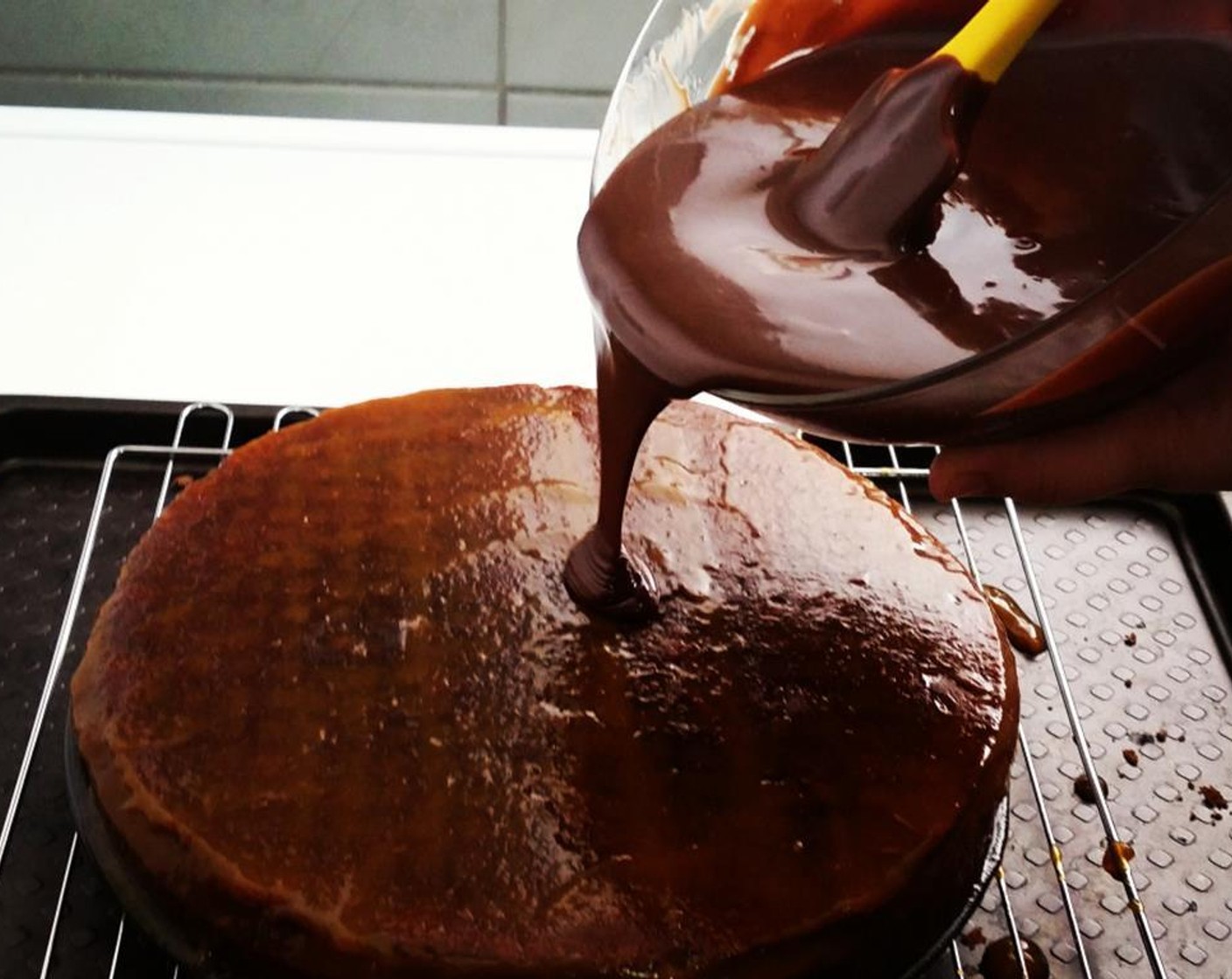 step 18 Pour the chocolate glaze over the top of the cake, first around the edges, then in the middle. Spread the excess glaze over any bare spots using a metal offset spatula. Before the glaze has a chance to set, move the cake to a serving platter.