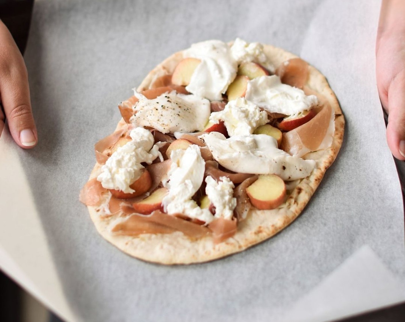 step 2 Arrange Prosciutto di Parma (6) in waves on top of the flatbreads, followed by White Peaches (2). Using your hands, roughly tear apart the Burrata Cheese (2) and wedge  the cheese in between the other toppings.