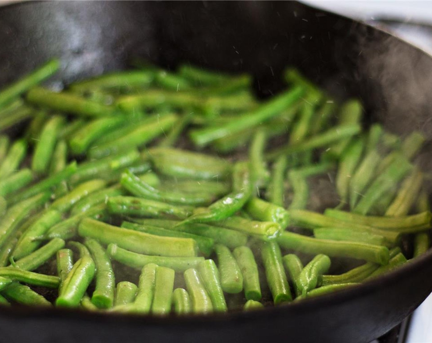 step 5 The beans should have turned bright green. Add about 1/4 cup of water to the pan. Cook another 2 minutes, until the water is mostly gone.