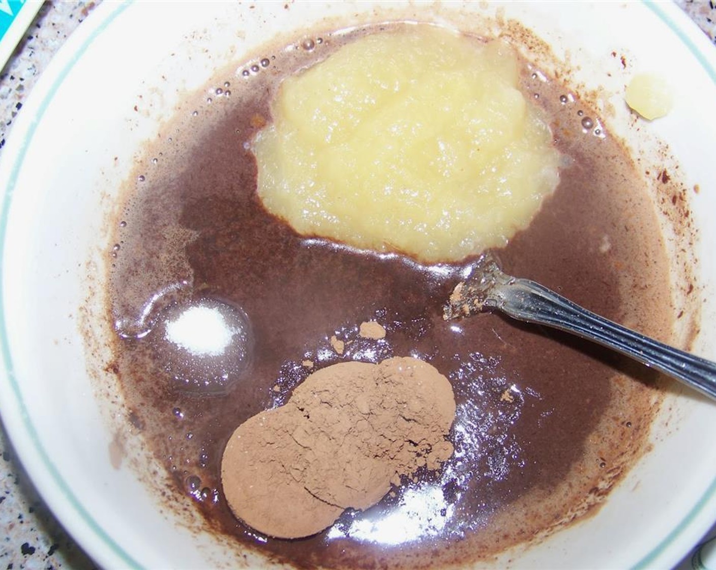 step 2 Into the melted chocolate, add the Apple Sauce (1/4 cup), Vanilla Extract (1/2 tsp), Unsweetened Cocoa Powder (1/2 Tbsp), and Granulated Sugar (1/2 Tbsp). Mix well.