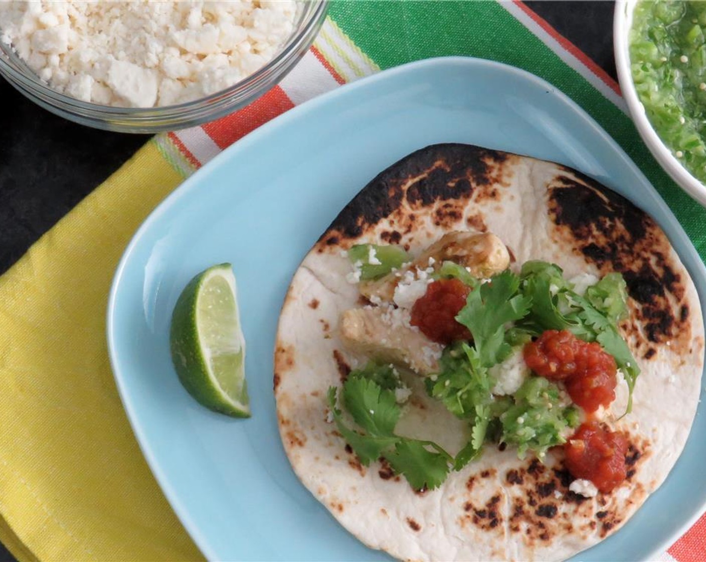step 12 To serve: Place a few strips of chicken in a tortilla. Top with sliced onion and poblano peppers, tomatillo salsa, Queso Fresco (to taste), cilantro, and a squeeze of lime.