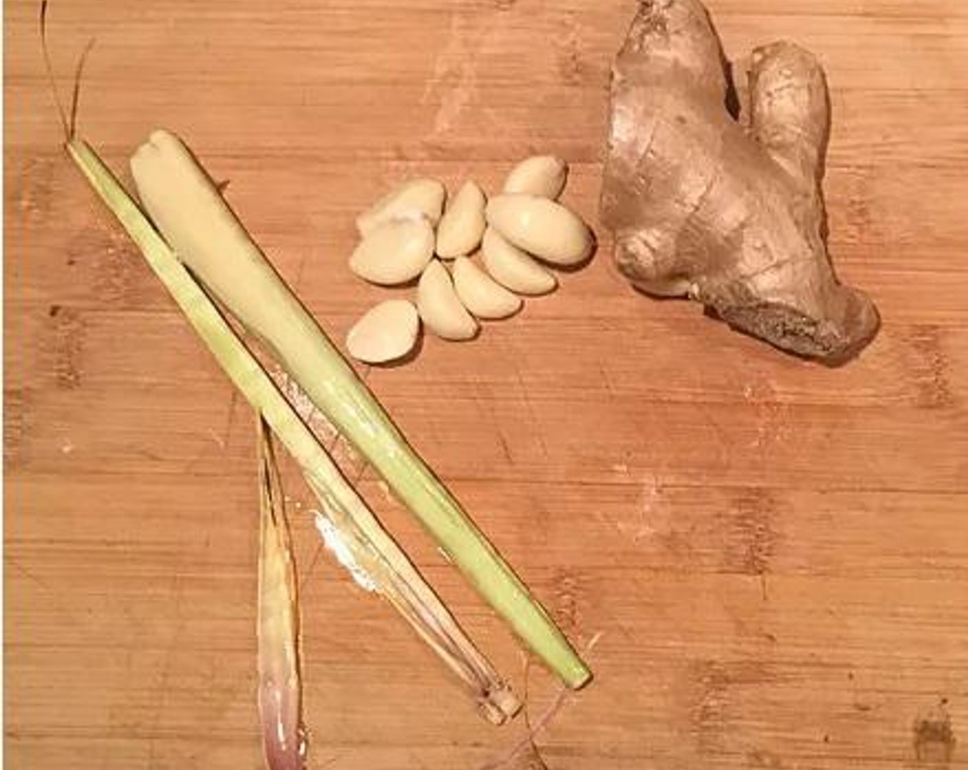 step 4 Prepare the aromatics.  Halve the Lemongrass (2 stalks), peel and smash the Garlic (5 cloves) with the side of your knife, and peel and thinly slice your Fresh Ginger (1).