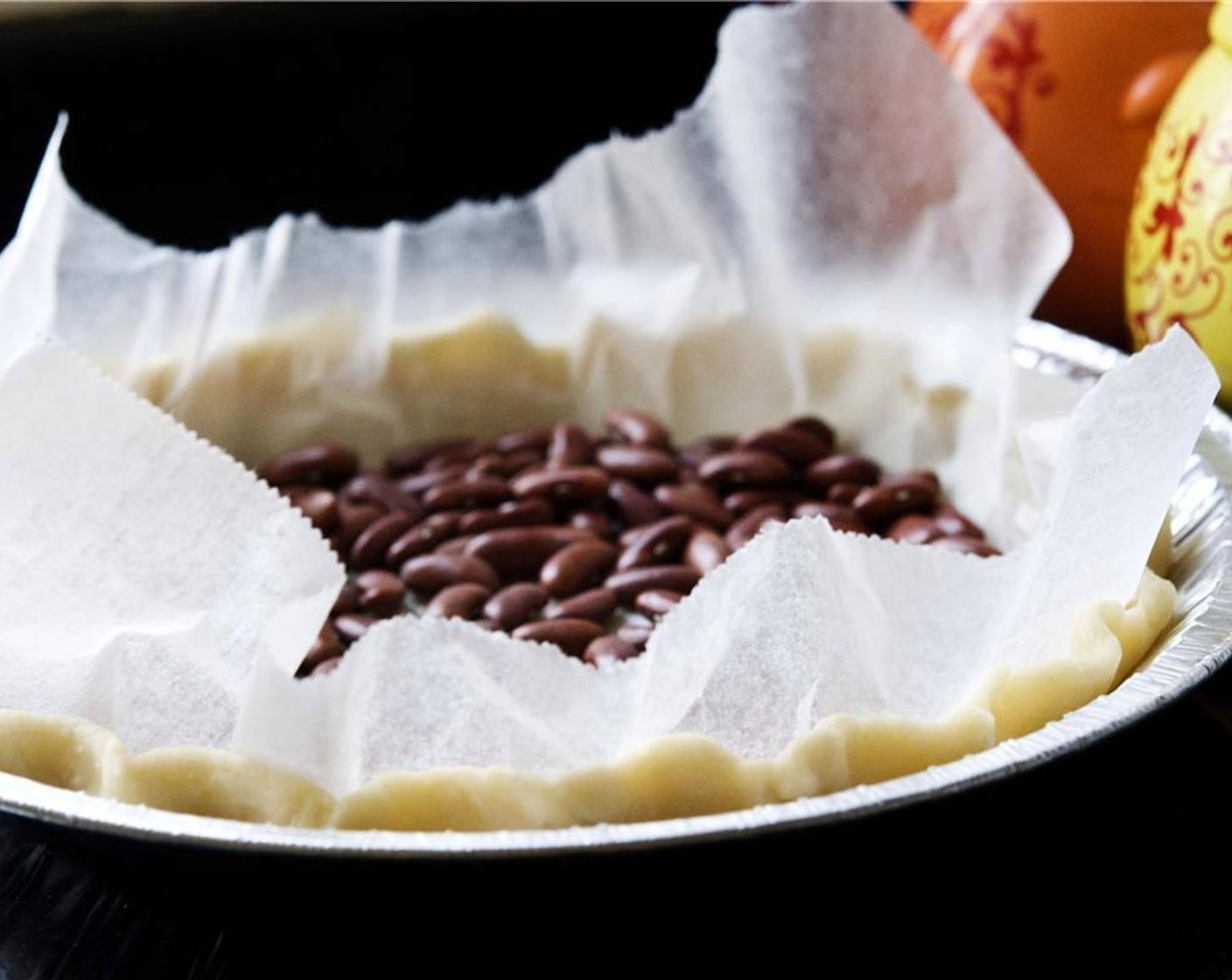 step 3 To prebake the crust, place a sheet of baking paper over the pastry and fill with something heavy, like beans or small stones.