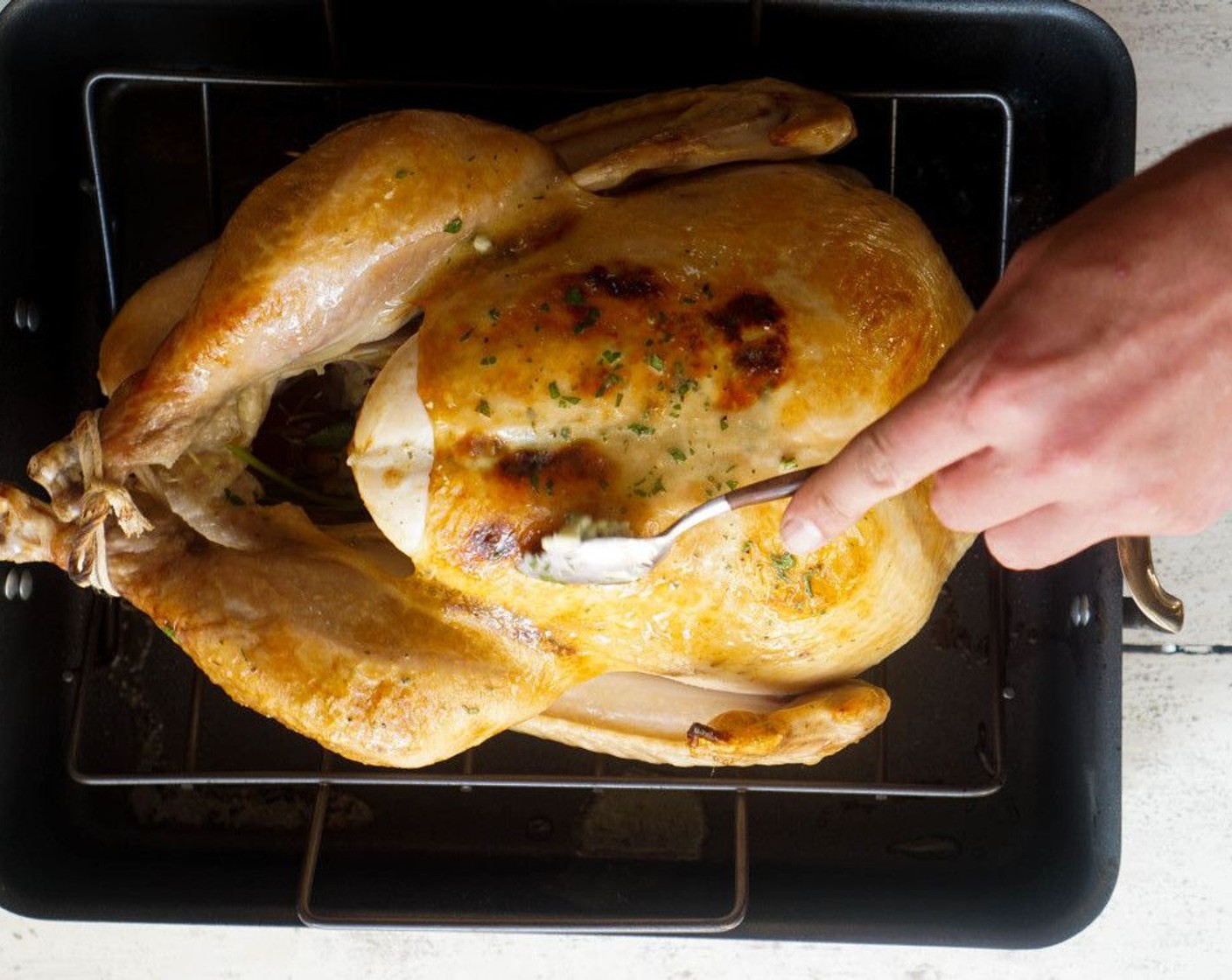 step 13 Reduce the oven to 350 degrees F (180 degrees C), remove the turkey (or slide out the oven grate) to dollop the remaining butter over the skin. Cover loosely with a foil triangle if the skin is getting dark.