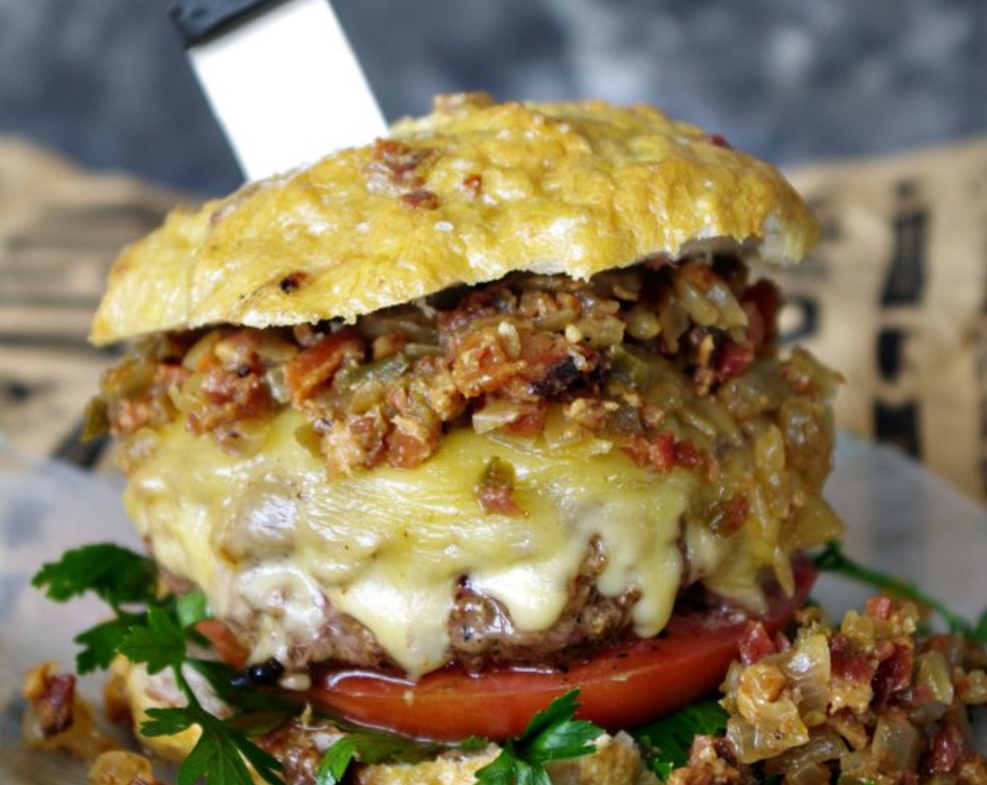 step 16 Build burger by adding roughly chopped Italian Flat-Leaf Parsley (to taste) and a Tomato (1) slice on a the bottom of a sliced pretzel bun, add burger, and top with bacon jam and pretzel bun top.