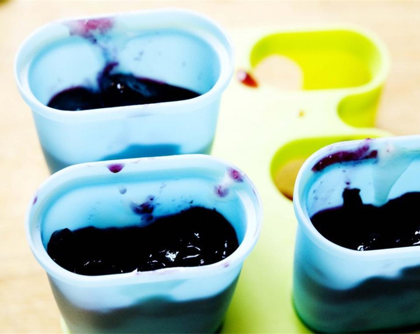 step 4 In your popsicle molds, pour one tablespoon of blueberries, followed by one tablespoon of yogurt then blueberries again.