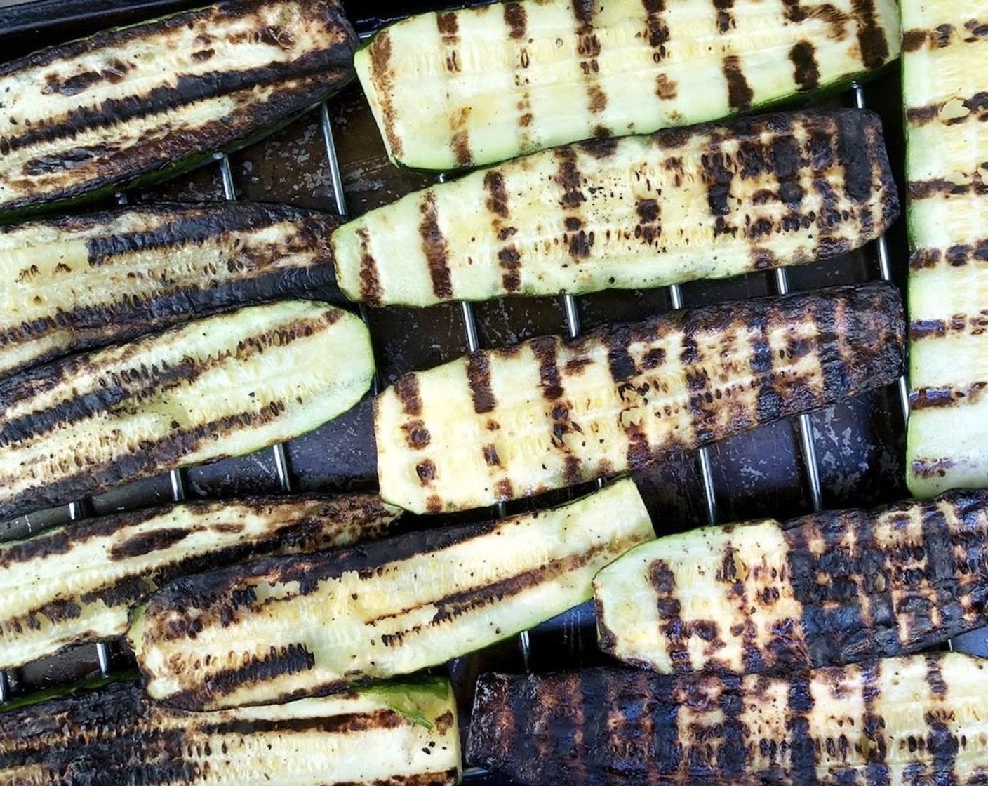 step 2 Lightly coat zucchini slices with Olive Oil (as needed) on one side, preferably the cut side. Season with Sea Salt (to taste) and Ground Black Pepper (to taste). Working in batches, grill zucchini on the rack of a covered grill over high heat on the coated side for 4-8 minutes, or until char marks just begin to form. Remove and set aside.