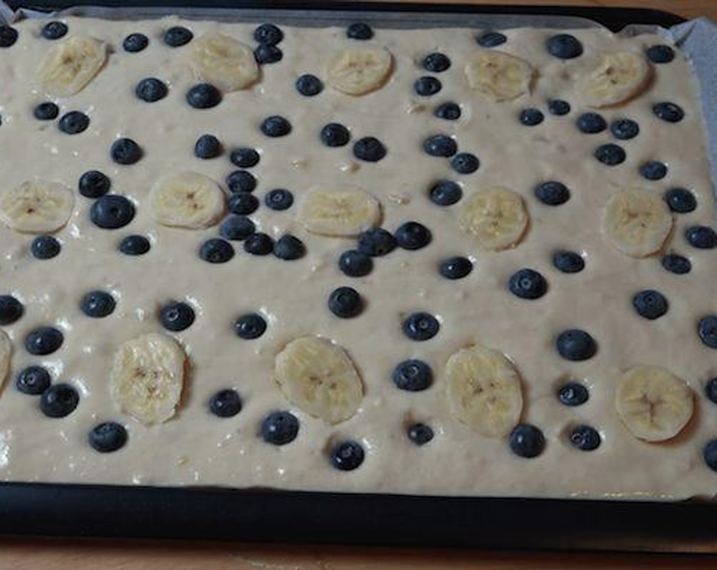 step 4 Lightly grease a sheet pan with spray on oil and line with some non-stick baking paper. Pour the batter in and carefully spread the batter until is even all over. Carefully place some Sliced Banana and Fresh Blueberries (to taste) on top of the batter and gently press down on the blueberries so that they stick to the batter.
