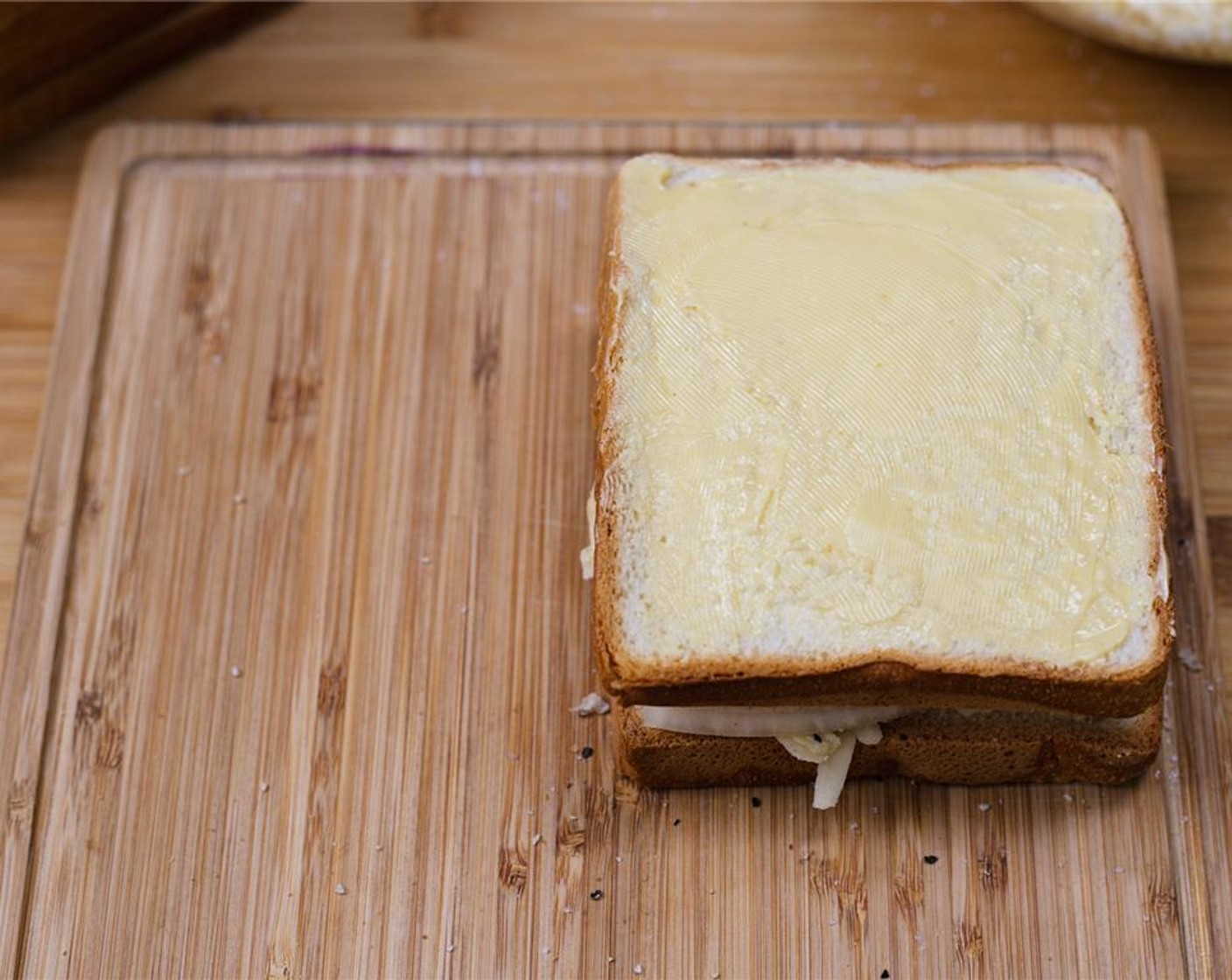 step 8 Place unbuttered side down on top of the sandwich. Press down gently to make sure the filling is snug between the two slices of bread. Repeat with the remaining slices of bread, cheese, sliced tomatoes and onion.