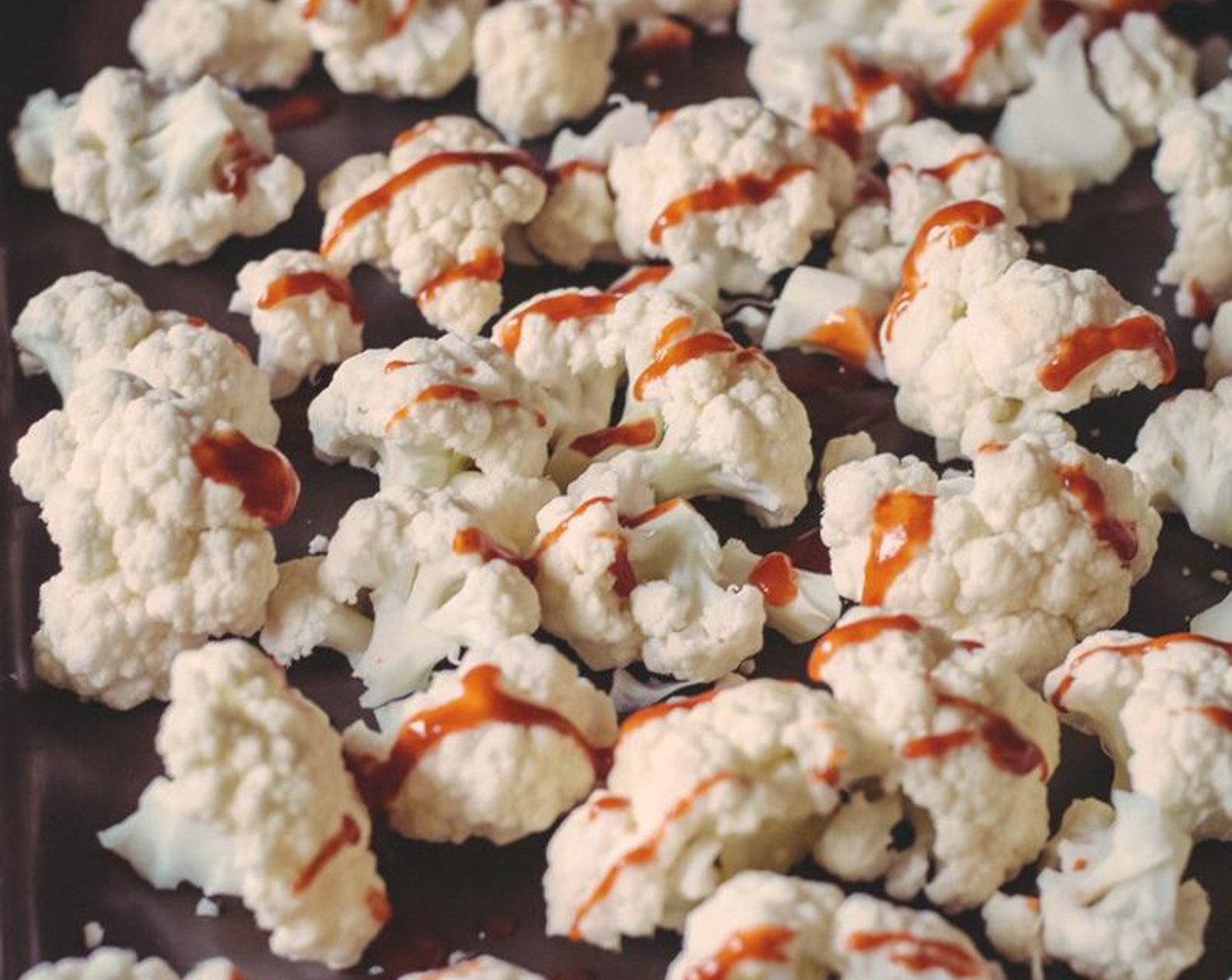 step 2 Wash and break Cauliflower (1 head), into small pieces. Arrange the cauliflower on prepared baking sheet in a single layer and drizzle with Sriracha (1 Tbsp) Bake for 10 minutes.