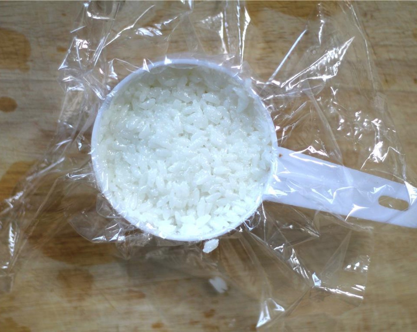 step 12 Wet your hands again and top with another 2 tbsp. of rice.  Flip and tap onto a plate, pulling the plastic wrap a little to remove.