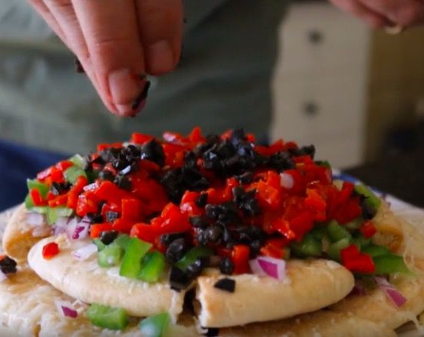 step 7 Top off the cheesy pita chips with the Red Onion (1/2), Green Bell Pepper (1), Jarred Roasted Red Peppers (3), Black Olives (8), Sea Salt (to taste) and Ground Black Pepper (to taste).