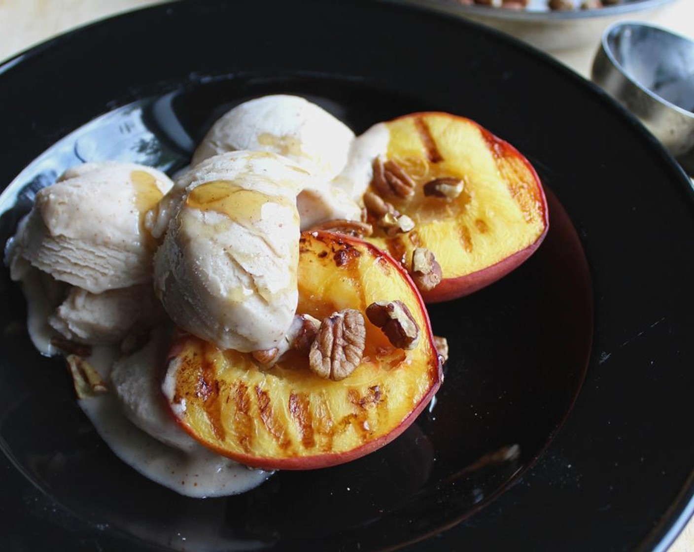 step 5 Fill your bowl with grilled peaches, a couple scoops of Vanilla Ice Cream (2 cups), a drizzle of Honey (1/4 cup) and some Pecans (1/4 cup).
