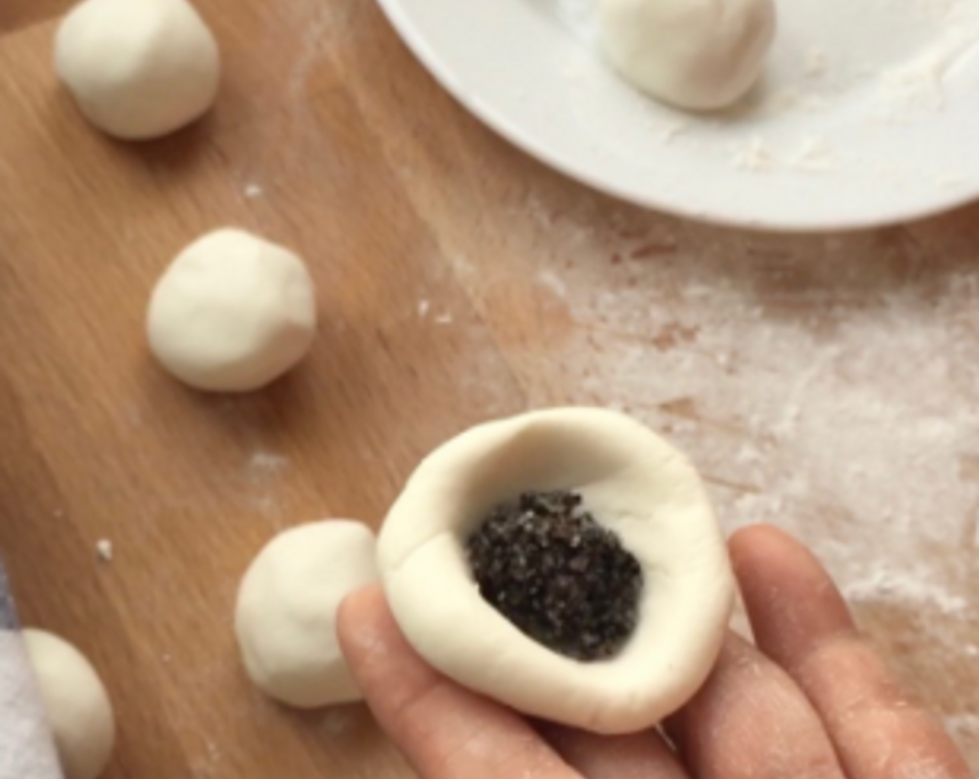 step 21 Take a piece of the dough ball and flatten. Then place 1 teaspoon of sesame paste filling in the middle.