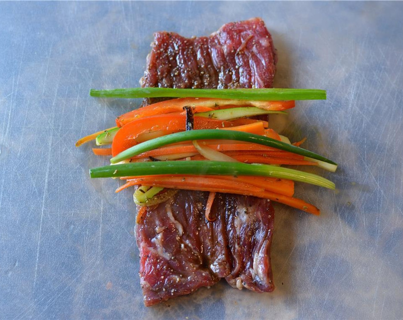 step 12 To assemble the steak rolls, simply take a strip of the marinated steak and lay it with the short side towards you. Place the veggies and Scallion (1 bunch) in the middle and roll the beef up over the filling.