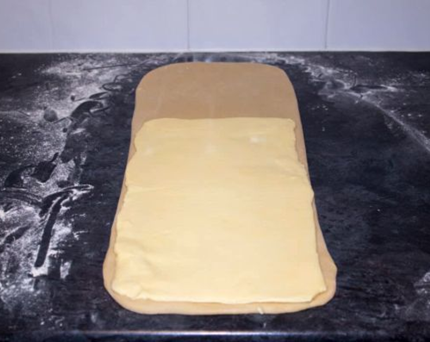 step 7 Then take the butter rectangle and place it over the bottom 2 thirds of the dough. Fold the top third over so it overlaps half of the butter.