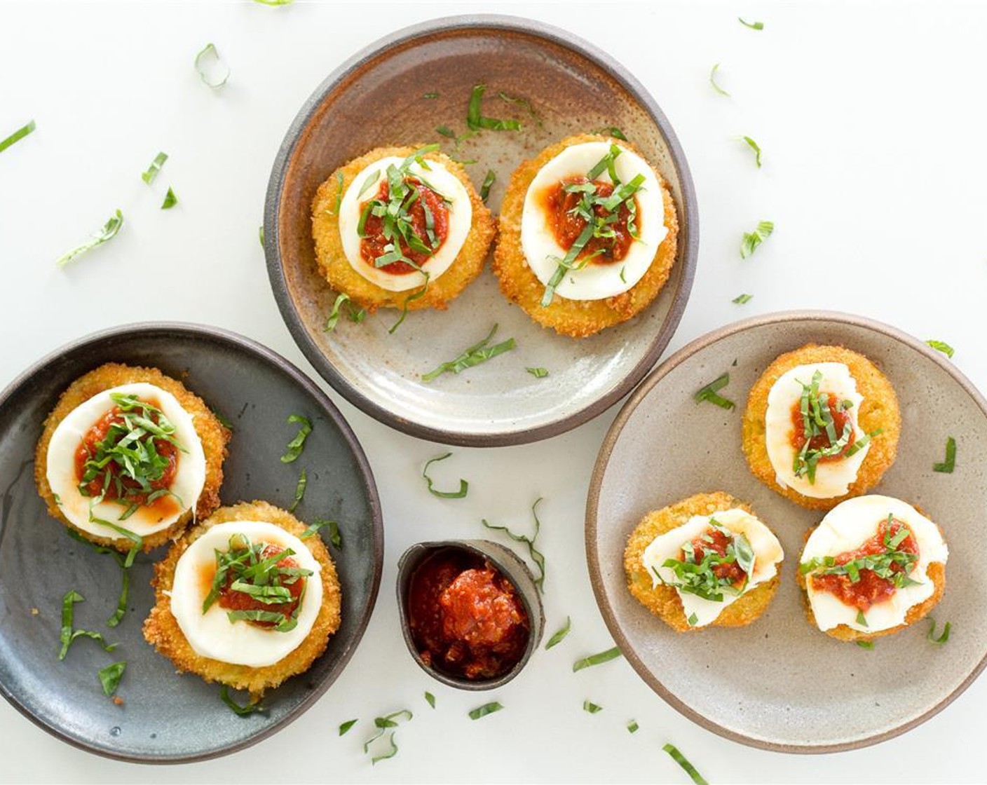 step 10 To assemble, starting with the bottom layer, place a fried green tomatoes on a plate, top with a slice of mozzarella, then add about 1/2 tbsp of Marinara Sauce (2 cups) and finally place a few of the chopped basil leaves on top. Serve immediately.