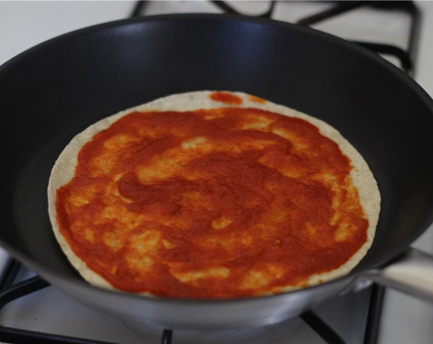 step 1 Put one of the Tortillas (2) on a hot skillet and slap on some Marinara Sauce (2 Tbsp).