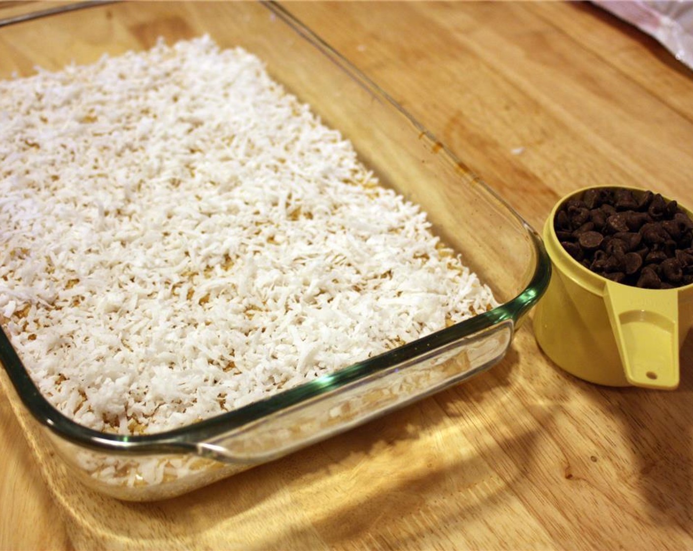 step 7 Next, sprinkle on the Sweetened Coconut Flakes (1 1/3 cups) evenly over the top of the walnuts.