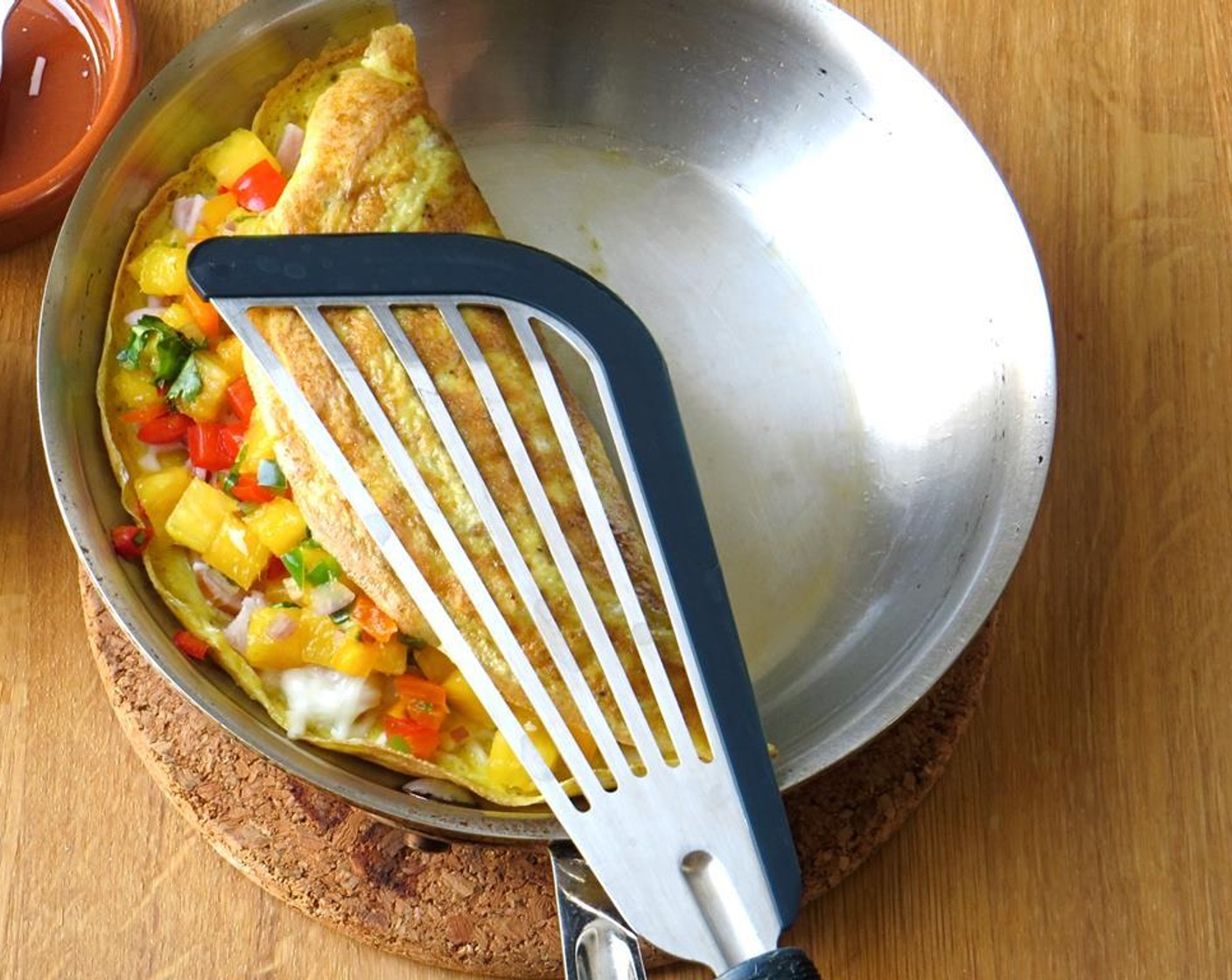 step 9 Using a very thin and flexible spatula (a fish spatula if you have one), carefully fold the omelet over on itself and lightly press with the spatula. Continue to cook for 30 seconds or so, holding the top of the omelet in place.