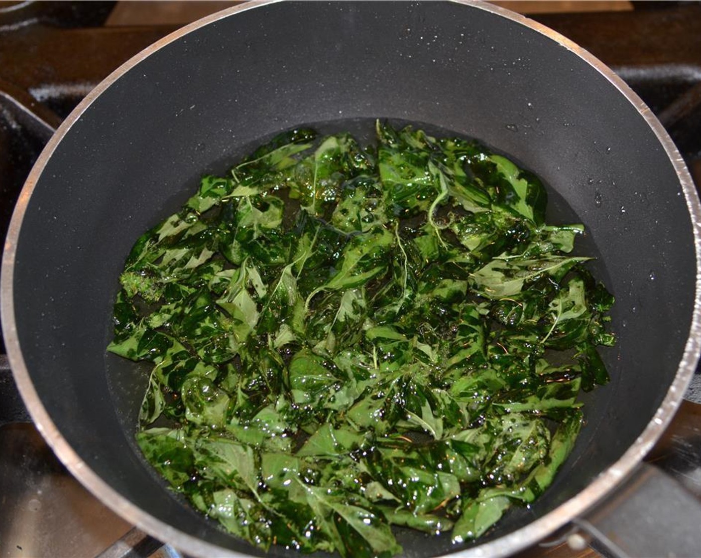 step 5 Heat the oil and fry the basil leaves until they look translucent and dark green, but not burned.