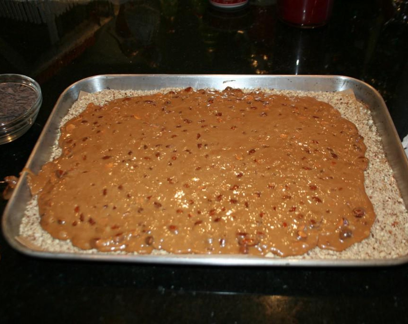 step 6 Then pour your hot candy mixture on top of the almond meal and spread with an offset spatula to make smooth and even. While your candy is still hot add your chocolate. This way the heat from the candy will melt it nicely for you.