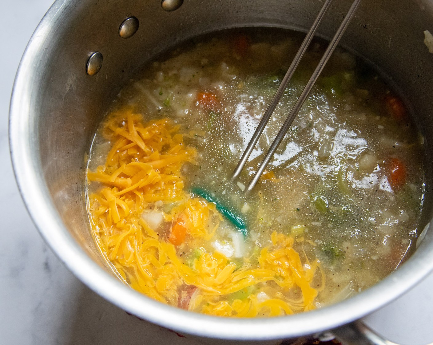 step 5 Remove the pan from the heat and add handfuls of Sharp Cheddar Cheese (1 block) at a time, stirring to melt between each addition.