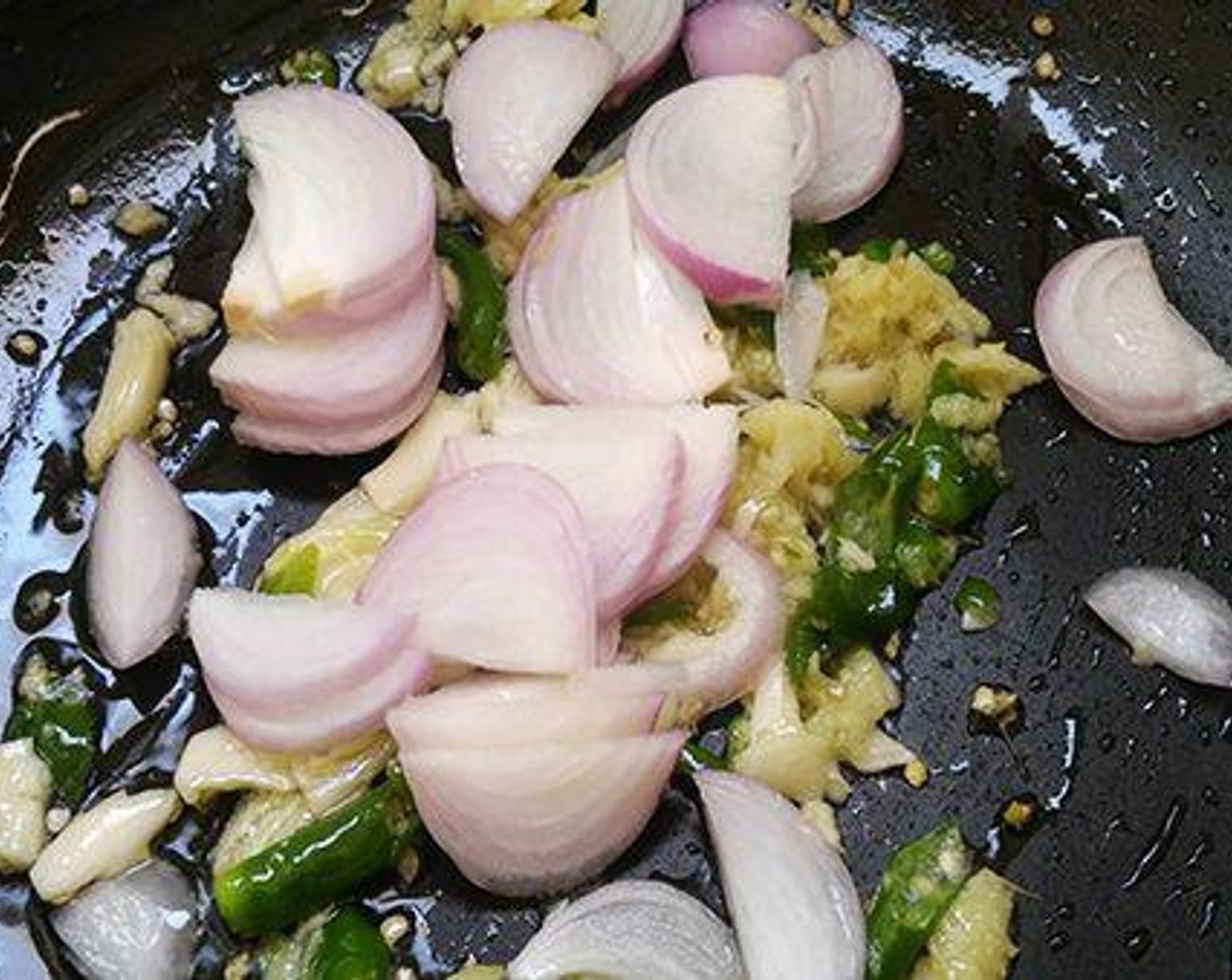 step 2 To the same pan add Oil (1 Tbsp) and add crush Fresh Ginger (1 piece), Garlic (5 cloves), and Green Chili Peppers (2). Saute for three to four minutes and add sliced Onion (1).