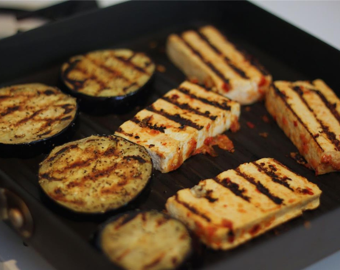 step 6 Rub the sauce on the extra firm tofu slabs to coat. Place them on the grill pan. Flip the eggplant and tofu when both have good grill marks. Keep warm in the microwave when done.