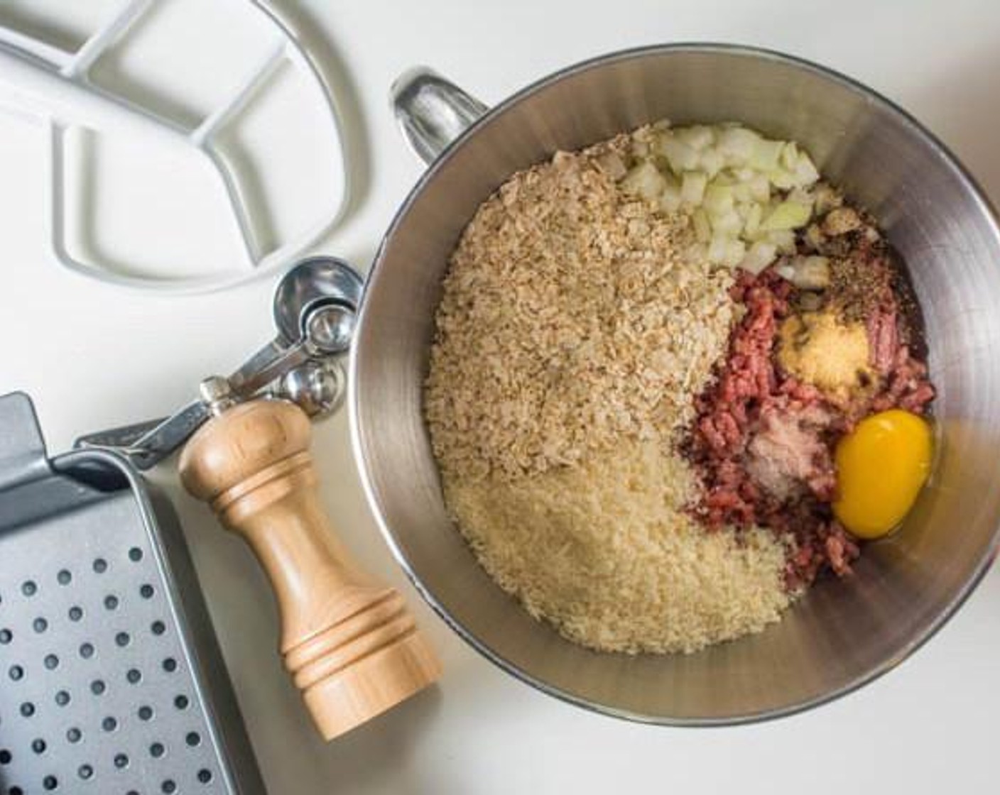 step 2 Combine Ground Beef (1.5 lb), Egg (1), Salt (1 tsp), Freshly Ground Black Pepper (1/2 tsp), McCormick® Garlic Powder (1 tsp), Onion (1/2), Oats (1 cup), and Panko Breadcrumbs (1 cup) in a mixer or by hand.