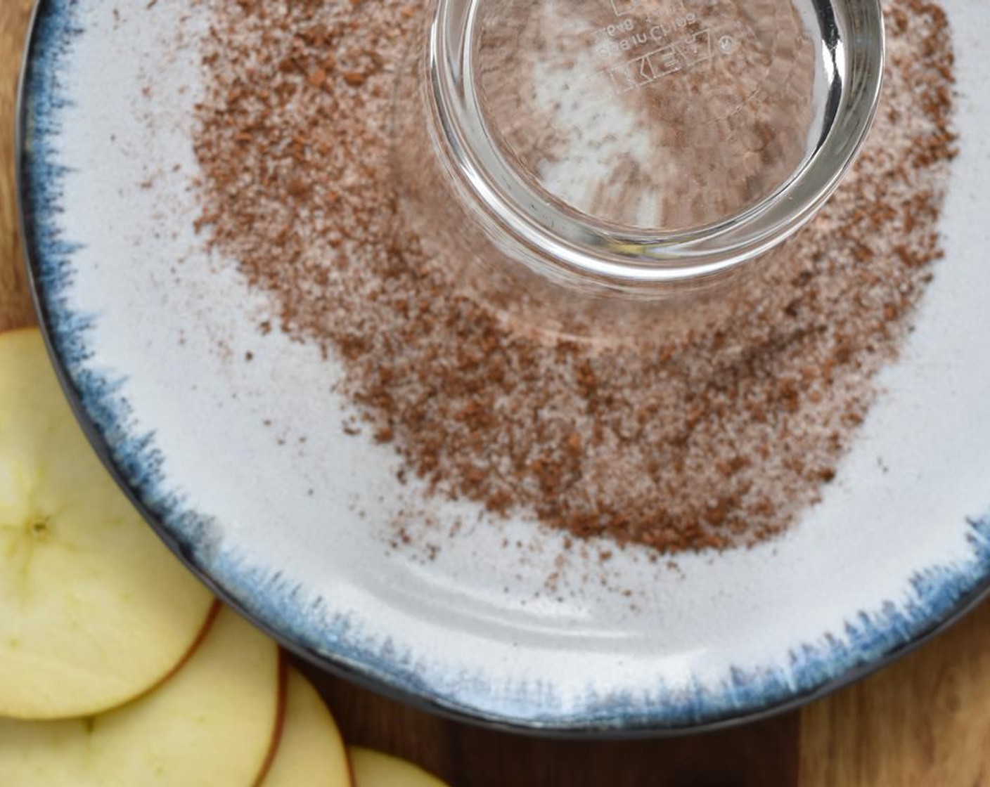 step 4 When you are ready to pour the drinks, thinly slice the Apple (1). Combine Ground Cinnamon (1 tsp) and Granulated Sugar (3 Tbsp) in a dish. Use the lemon rind to dampen the rim of the glasses, then dip them into the dish with the cinnamon and sugar.