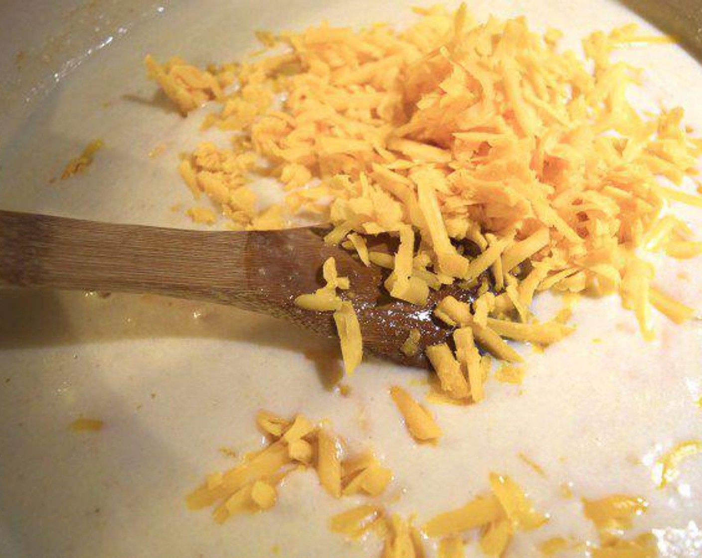 step 7 Next, slowly pour the eggs into the pot with the rest of the bechamel. Stir together over low heat for about 2 minutes. Then, remove the pot from the heat and stir in 3 cup of Extra Sharp Cheddar Cheese (680 g). Season with Salt (1 dash) and Ground Black Pepper (1 dash).