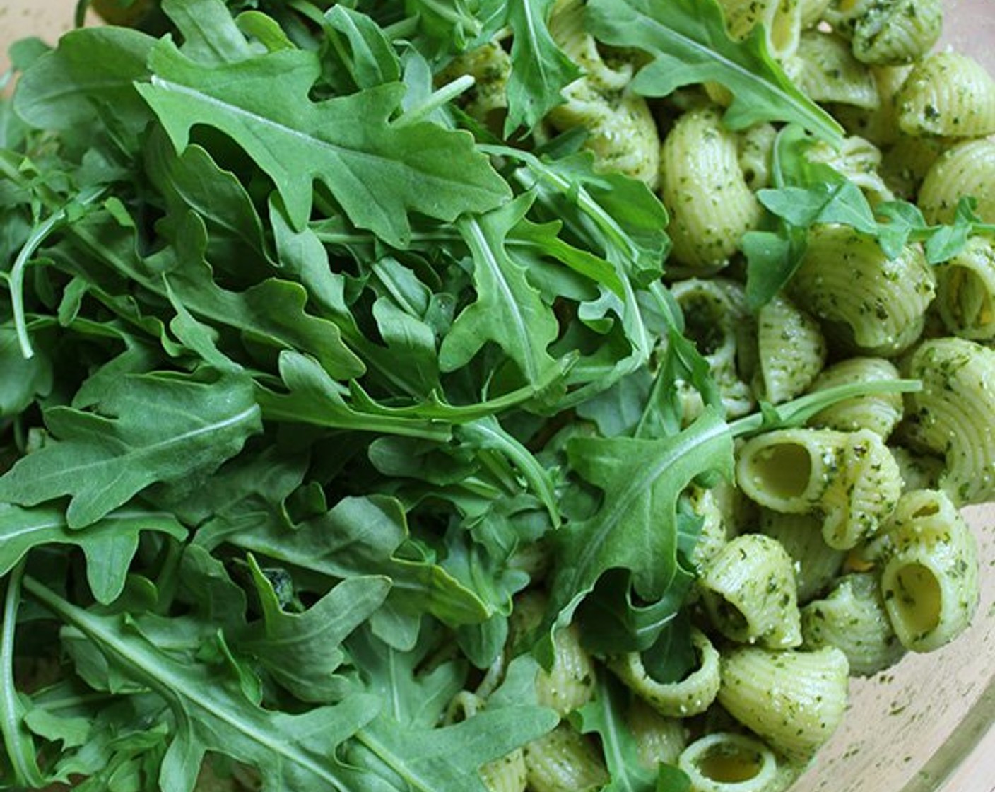 step 6 Add the pesto to the cooked pasta and toss well to coat. Add the Baby Arugula (2 cups) and the remaining Pine Nuts (2 Tbsp) and toss again.