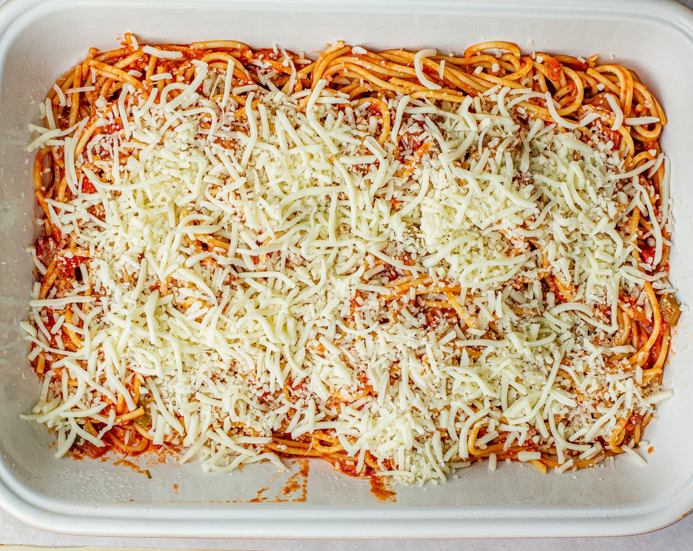 step 7 Add half the spaghetti to the baking pan. Sprinkle half of the cheese mixture over the top.