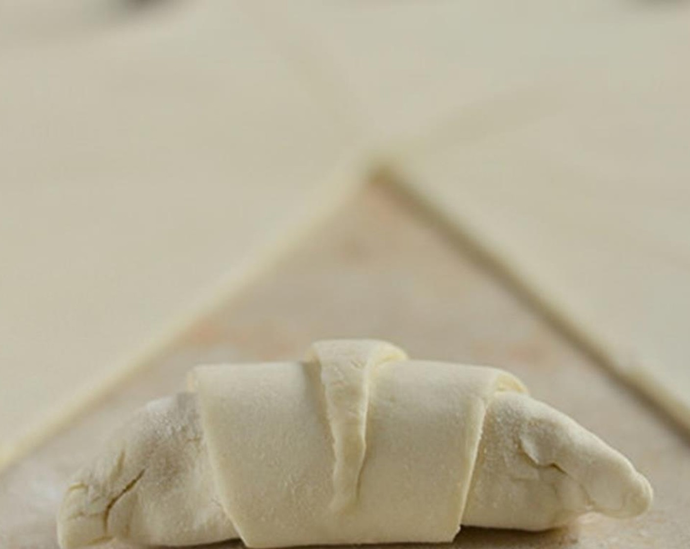 step 6 Now pinch the tip of the triangle so that it sticks. That way the croissant won't come apart as the pastry puffs up in the oven.